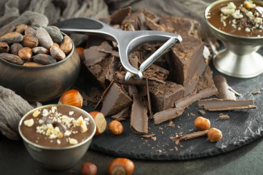 Eskimiş bir arka planda kakao çekirdeği ve fındıklı siyah çikolata..