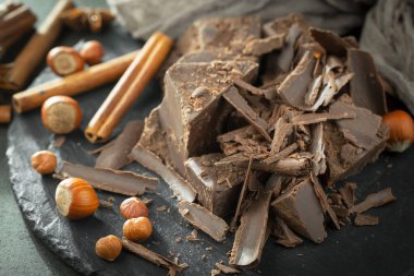 Eskimiş bir arka planda kakao çekirdeği ve fındıklı siyah çikolata..