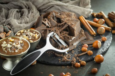 Eskimiş bir arka planda kakao çekirdeği ve fındıklı siyah çikolata..