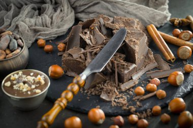 Eskimiş bir arka planda kakao çekirdeği ve fındıklı siyah çikolata..