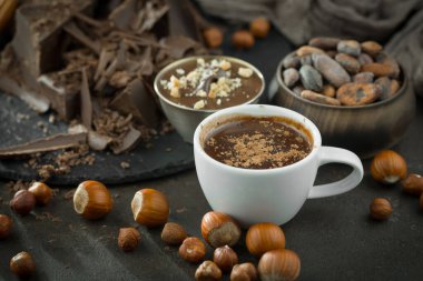 Eskimiş bir arka planda kakao çekirdeği ve fındıklı siyah çikolata..