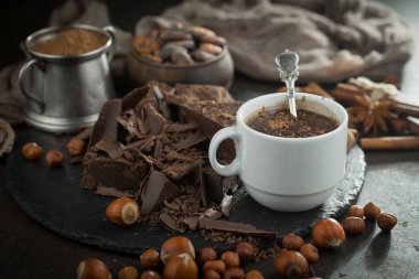 Eskimiş bir arka planda kakao çekirdeği ve fındıklı siyah çikolata..