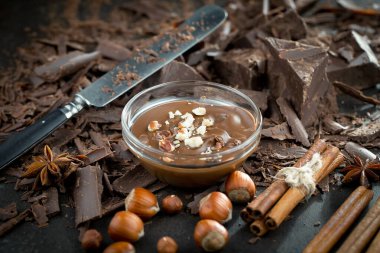 Eskimiş bir arka planda kakao çekirdeği ve fındıklı siyah çikolata..