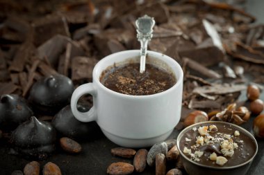 Eskimiş bir arka planda kakao çekirdeği ve fındıklı siyah çikolata..