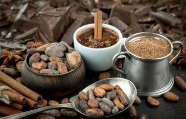 Eskimiş bir arka planda kakao çekirdeği ve fındıklı siyah çikolata..