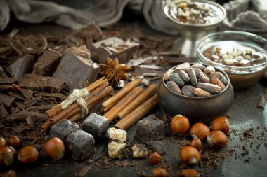 Eskimiş bir arka planda kakao çekirdeği ve fındıklı siyah çikolata..