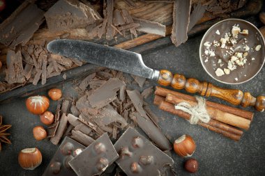 Eskimiş bir arka planda kakao çekirdeği ve fındıklı siyah çikolata..