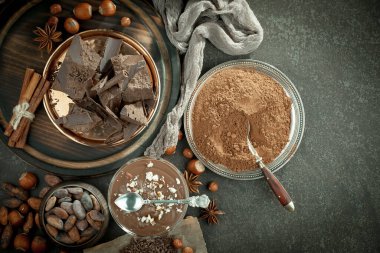 Eskimiş bir arka planda kakao çekirdeği ve fındıklı siyah çikolata..