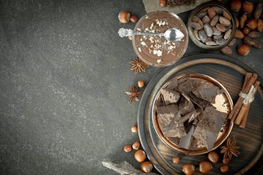 Eskimiş bir arka planda kakao çekirdeği ve fındıklı siyah çikolata..