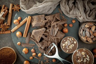 Eskimiş bir arka planda kakao çekirdeği ve fındıklı siyah çikolata..