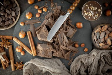 Eskimiş bir arka planda kakao çekirdeği ve fındıklı siyah çikolata..