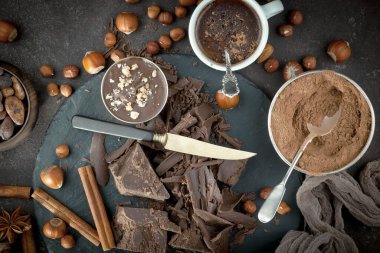 Eskimiş bir arka planda kakao çekirdeği ve fındıklı siyah çikolata..