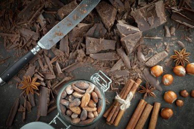 Eskimiş bir arka planda kakao çekirdeği ve fındıklı siyah çikolata..