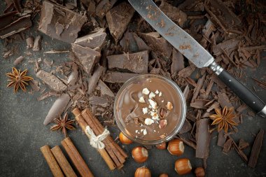 Eskimiş bir arka planda kakao çekirdeği ve fındıklı siyah çikolata..