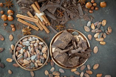 Eskimiş bir arka planda kakao çekirdeği ve fındıklı siyah çikolata..