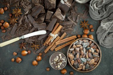 Eskimiş bir arka planda kakao çekirdeği ve fındıklı siyah çikolata..