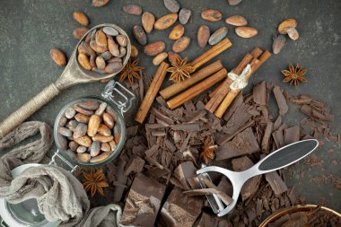 Eskimiş bir arka planda kakao çekirdeği ve fındıklı siyah çikolata..