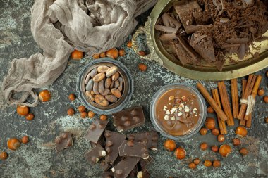 Eskimiş bir arka planda kakao çekirdeği ve fındıklı siyah çikolata..