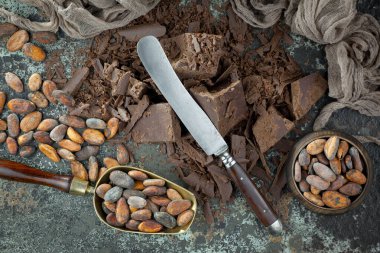 Eskimiş bir arka planda kakao çekirdeği ve fındıklı siyah çikolata..