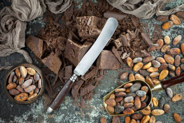 Eskimiş bir arka planda kakao çekirdeği ve fındıklı siyah çikolata..