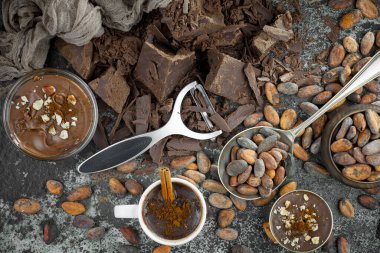 Eskimiş bir arka planda kakao çekirdeği ve fındıklı siyah çikolata..