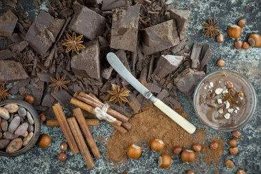 Eskimiş bir arka planda kakao çekirdeği ve fındıklı siyah çikolata..