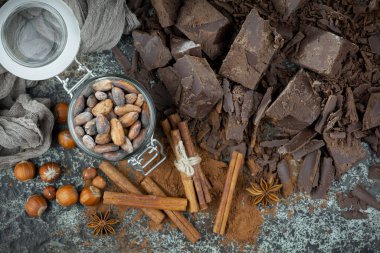 Eskimiş bir arka planda kakao çekirdeği ve fındıklı siyah çikolata..