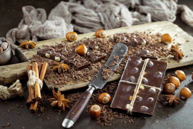 Eskimiş bir arka planda kakao çekirdeği ve fındıklı siyah çikolata..