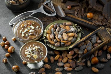 Eskimiş bir arka planda kakao çekirdeği ve fındıklı siyah çikolata..