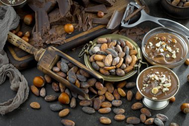 Eskimiş bir arka planda kakao çekirdeği ve fındıklı siyah çikolata..