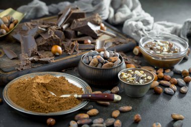 Eskimiş bir arka planda kakao çekirdeği ve fındıklı siyah çikolata..