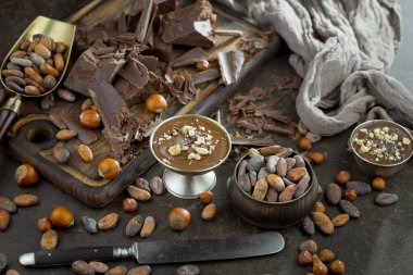 Eskimiş bir arka planda kakao çekirdeği ve fındıklı siyah çikolata..