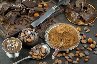 Eskimiş bir arka planda kakao çekirdeği ve fındıklı siyah çikolata..