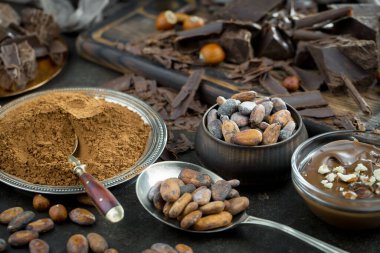 Eskimiş bir arka planda kakao çekirdeği ve fındıklı siyah çikolata..