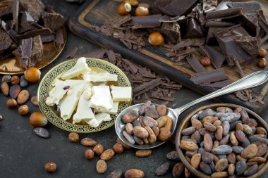 Eskimiş bir arka planda kakao çekirdeği ve fındıklı siyah çikolata..