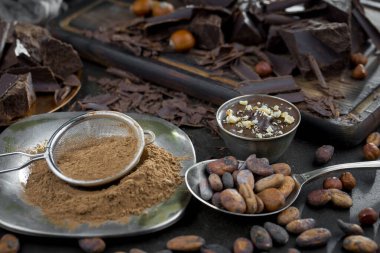 Eskimiş bir arka planda kakao çekirdeği ve fındıklı siyah çikolata..