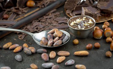 Eskimiş bir arka planda kakao çekirdeği ve fındıklı siyah çikolata..