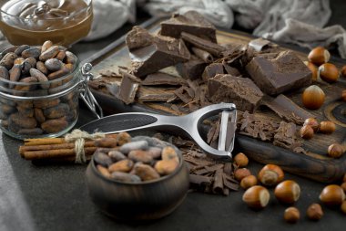 Eskimiş bir arka planda kakao çekirdeği ve fındıklı siyah çikolata..