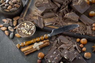 Eskimiş bir arka planda kakao çekirdeği ve fındıklı siyah çikolata..