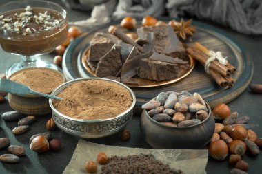 Eskimiş bir arka planda kakao çekirdeği ve fındıklı siyah çikolata..