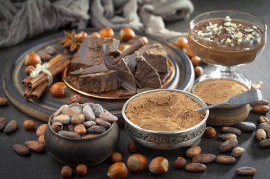 Eskimiş bir arka planda kakao çekirdeği ve fındıklı siyah çikolata..