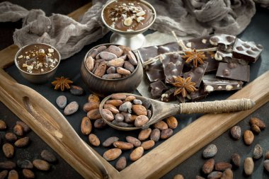 Eskimiş bir arka planda kakao çekirdeği ve fındıklı siyah çikolata..
