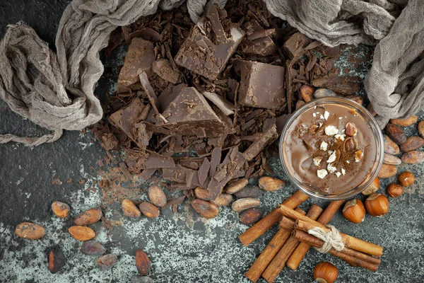 Eskimiş bir arka planda kakao çekirdeği ve fındıklı siyah çikolata..