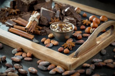 Eskimiş bir arka planda kakao çekirdeği ve fındıklı siyah çikolata..