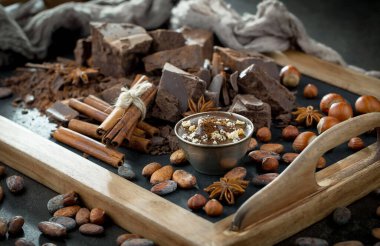 Eskimiş bir arka planda kakao çekirdeği ve fındıklı siyah çikolata..