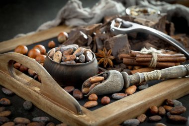 Eskimiş bir arka planda kakao çekirdeği ve fındıklı siyah çikolata..