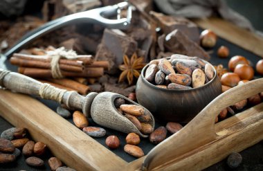 Eskimiş bir arka planda kakao çekirdeği ve fındıklı siyah çikolata..