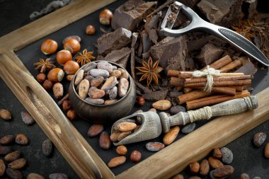 Eskimiş bir arka planda kakao çekirdeği ve fındıklı siyah çikolata..