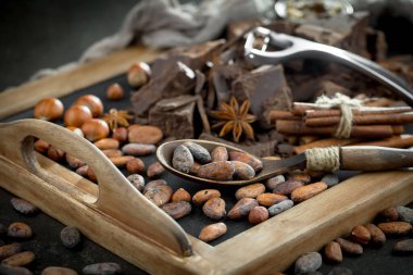 Eskimiş bir arka planda kakao çekirdeği ve fındıklı siyah çikolata..