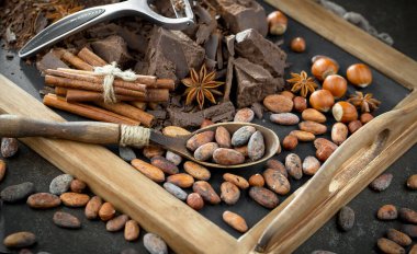 Eskimiş bir arka planda kakao çekirdeği ve fındıklı siyah çikolata..
